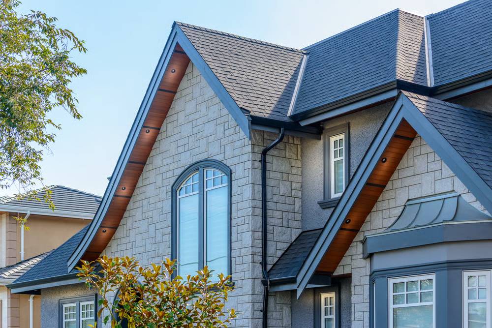 A newly finished dark gray seamless aluminum gutter installation on a clean home roofline.